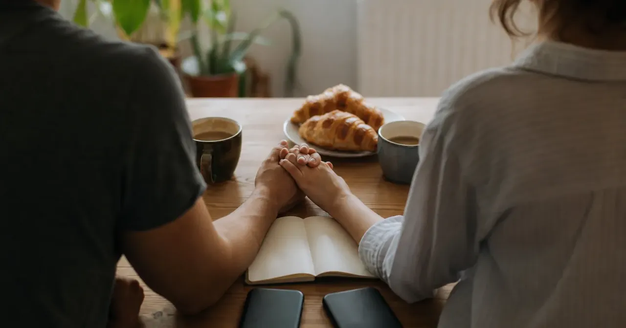 Couple de dos dans cuisine chaleureuse mains enlacées ce matin